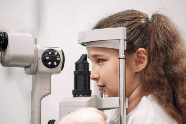 istock Examination of the child using a slit lamp. Microscope and focused light source. A device for high-precision examination of the eye to determine the condition of the lens. 2158381110