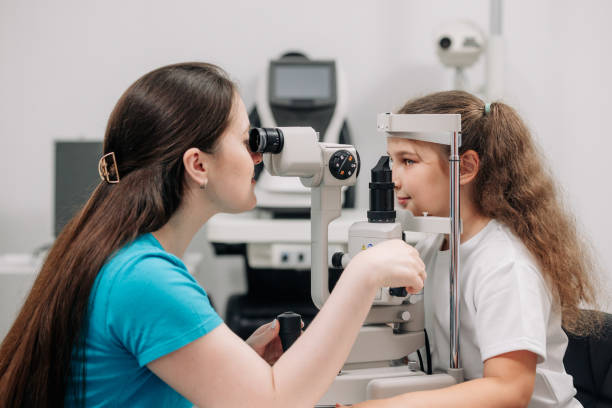 istock Examination of the child using a slit lamp. Microscope and focused light source. A device for high-precision examination of the eye to determine the condition of the lens. 2158381162