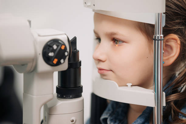 istock Examination of the child using a slit lamp. Microscope and focused light source. A device for high-precision examination of the eye to determine the condition of the lens. 2158381269