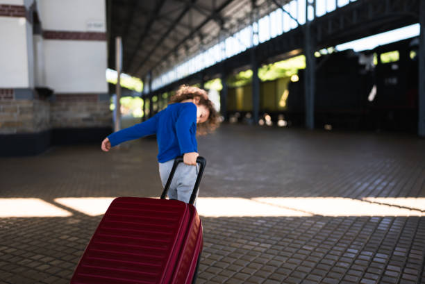 kid pushing his luggage in train station