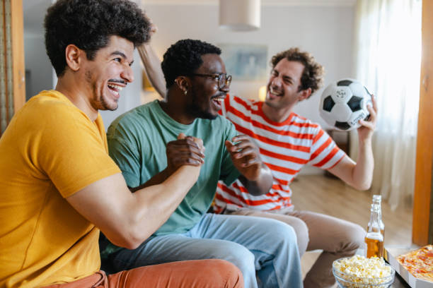 istock Happy soccer fans watching match at home 2158382484