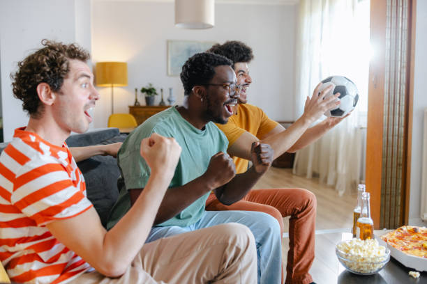 istock Happy soccer fans watching match at home 2158382485