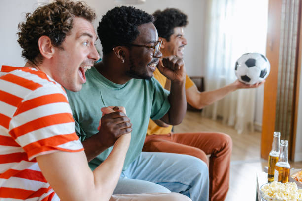 istock Happy soccer fans watching match at home 2158382506