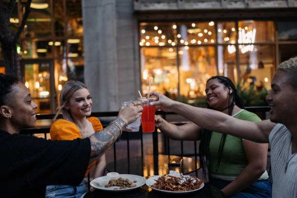 Group of friends toasting drinks at outdoor restaurant
