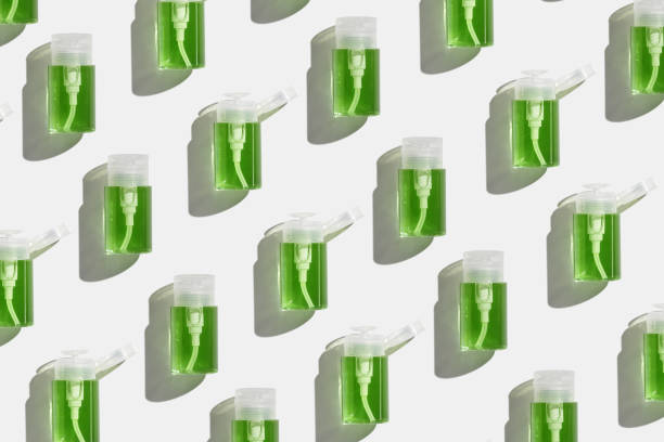 istock Transparent Pump dispensers with green colored liquid as pattern. Skincare essentials, spa beauty products on light background, Cosmetic bottles at sunlight, minimal top view geometric lauout 2158385506