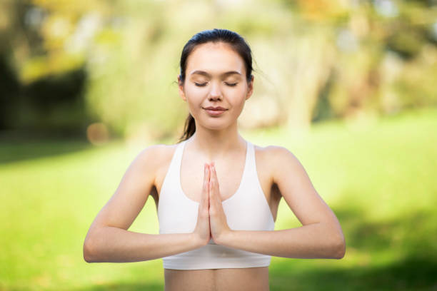 istock Tranquil young woman with eyes closed in Namaste pose, practicing mindful meditation in a bright 2158385754