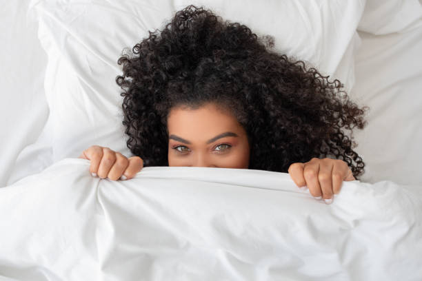 istock Woman Peeking Out From Under a Blanket 2158385860