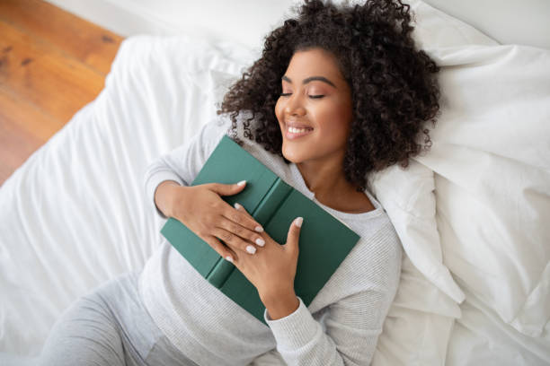 istock Woman Laying in Bed Holding a Book 2158385891