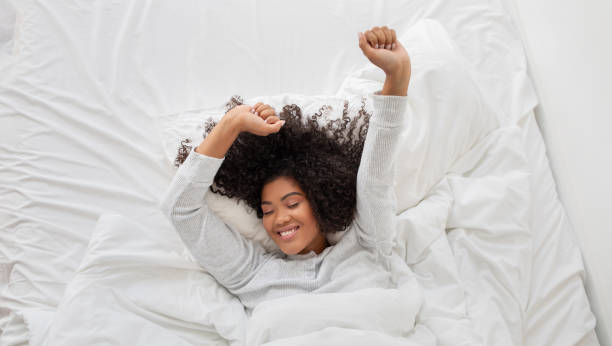 istock Young Woman Smiling and Stretching on a Comfortable White Bed 2158385901