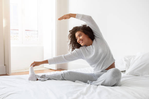 istock Woman Stretching on Bed With White Sheets 2158385919