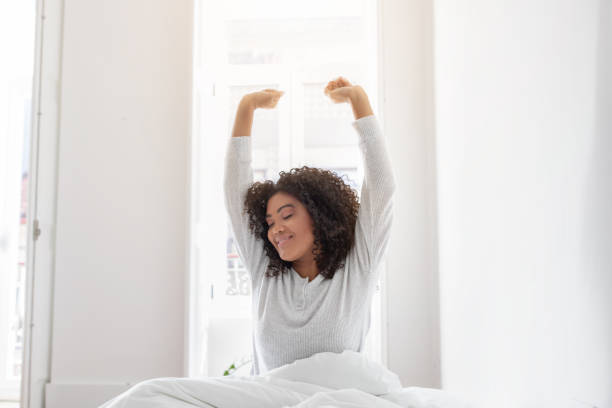 istock Woman Waking in Bed With Arms Raised 2158385937