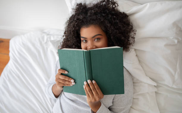 istock Woman Reading Book While Laying in Bed 2158385939