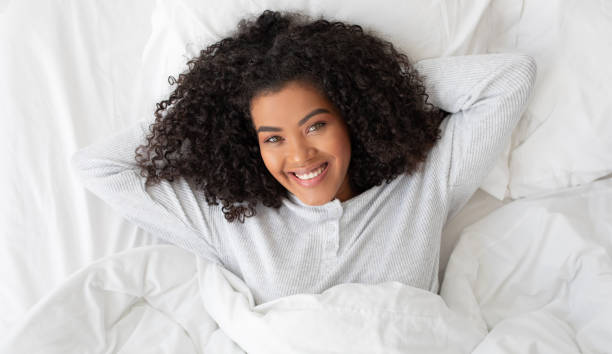 istock Relaxed Young Woman Smiling in Cozy White Bed 2158385940