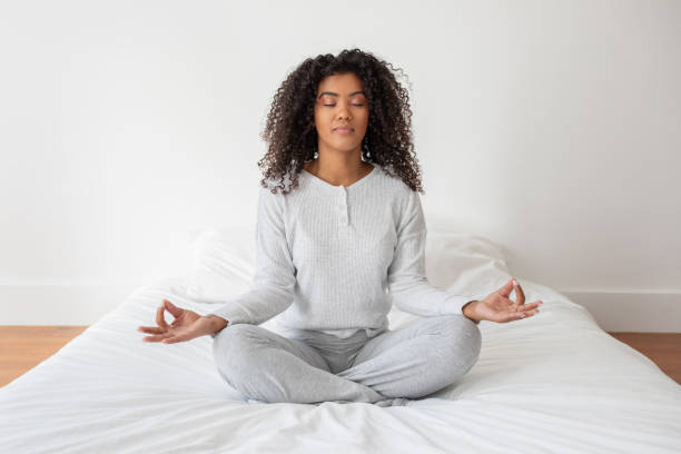istock Woman Sitting in Lotus Position on Bed 2158385948