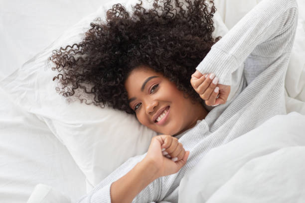 istock Smiling Young Woman Waking Up in a Cozy White Bed 2158385954