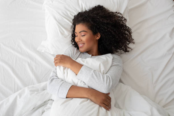 istock Serene Woman Embracing A Pillow While Resting In White Bed 2158386002