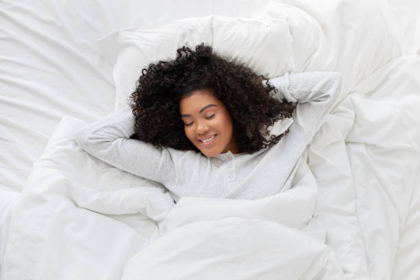 istock Woman Laying in Bed With White Sheets, Smiling 2158386006