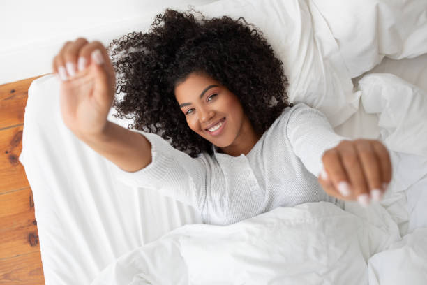 istock Woman Laying in Bed With White Sheets, Stretching Arms 2158386007