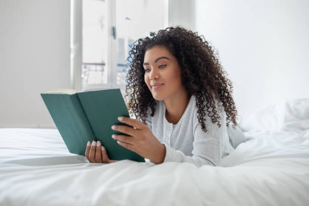 istock Woman Laying on Bed Reading a Book 2158386029