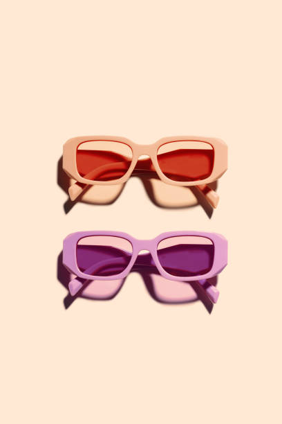 istock Two Colorful Sunglasses with pink and purple Frames on beige background, sunlight shadow, summer vacation, rest concept. Aesthetic top view eyeglasses, fashion eyewear product, minimal style 2158386293