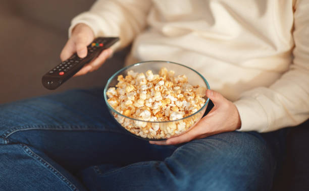 istock Man Holding Bowl of Popcorn and Remote Control, Cropped 2158386481