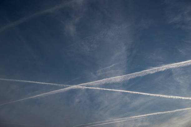 istock Planes trails in a slightly cloudy blue sky, viewed from the ground. 2158390479