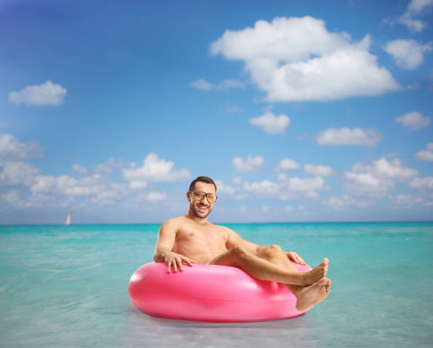 istock Handsome young man sitting on a swimming ring 2158392641