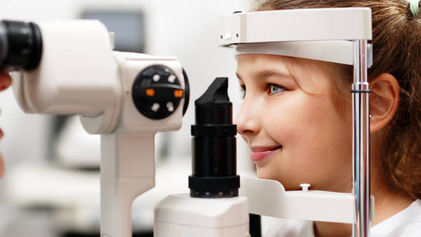 istock Examination of the child using a slit lamp. Microscope and focused light source. A device for high-precision examination of the eye to determine the condition of the lens. 2158392984