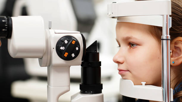 istock Examination of the child using a slit lamp. Microscope and focused light source. A device for high-precision examination of the eye to determine the condition of the lens. 2158393523
