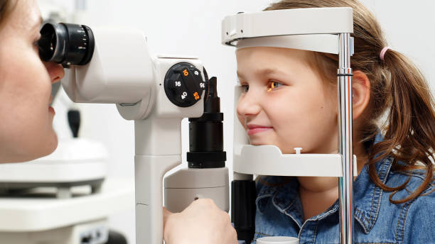 istock Examination of the child using a slit lamp. Microscope and focused light source. A device for high-precision examination of the eye to determine the condition of the lens. 2158393690