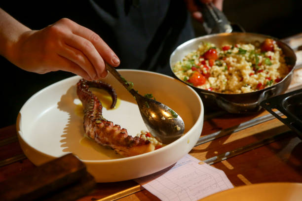 Chef preparing grilled octopus with couscous in the restaurant kitchen