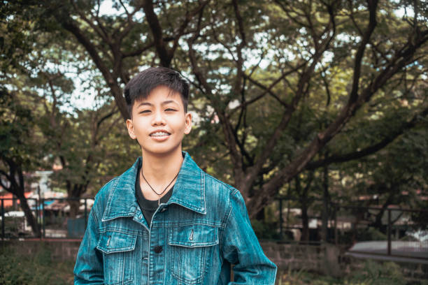 A young handsome lesbian woman in happy thoughts. Smiling about her healthy relationship and self-esteem. Standing outside the park.