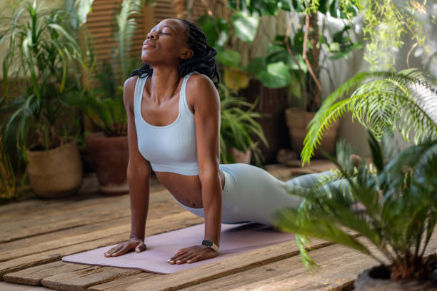 istock Relaxed african american woman doing snake pose, stretching body, developing flexibility on yoga mat 2158396347