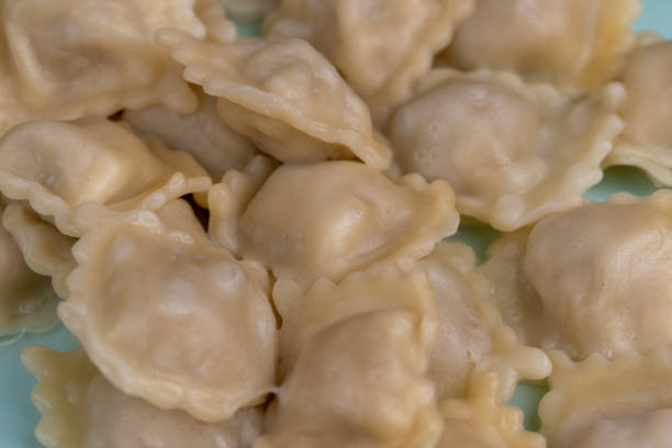 close-up of hands shaping a homemade dumpling pelmeni with a meat filling bowl spoon traditional cooking preparation recipe tutorials cultural family cuisine pelmeni making meals Slavic Eastern Europ