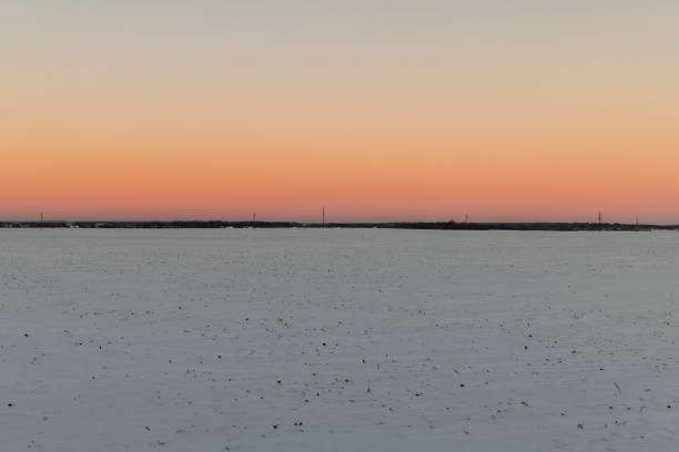 winter field covered with snow at sunset, beautiful multicolored sky at sunset in winter