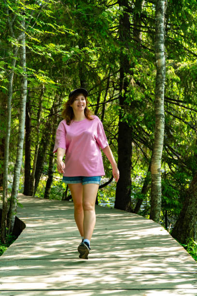 istock Smiling Woman Walking on Forest Boardwalk in Summer 2158404904