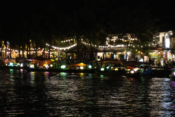 Experience the enchanting beauty of Hoi An, Vietnam, with boats and lanterns illuminating the ancient town. This picturesque scene captures the timeless charm and vibrant culture of this historic destination. Seen at night.