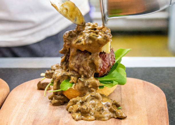 istock Chef hands putting sausage on the top of a hamburger on a restaurant kitchen. 2158407375