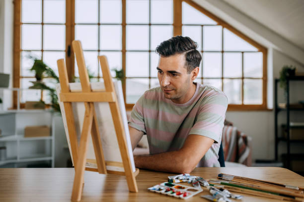 istock Casually clothed man painting on canvas at home 2158408260