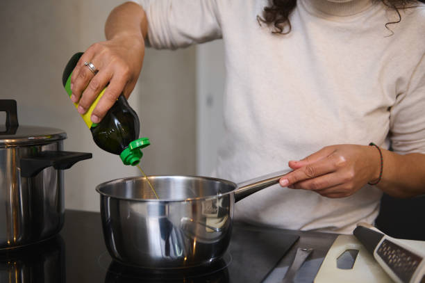 istock Woman pouring olive oil into a saucepan while cooking in kitchen 2158408790