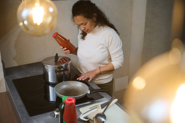 istock Woman cooking in modern kitchen with sauce bottle 2158410328