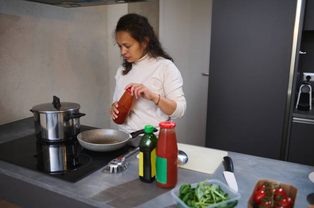 istock Woman preparing meal in modern kitchen with fresh ingredients 2158410794