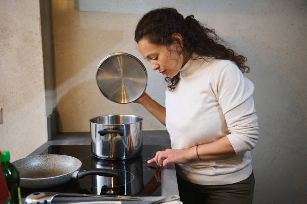 istock Woman cooking in modern kitchen, checking pot on stove 2158411434