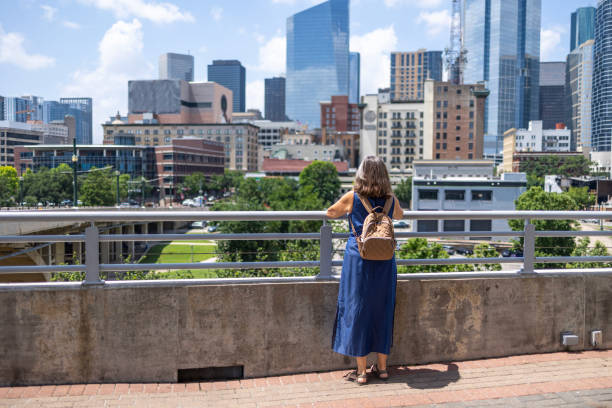istock Woman on bridge with backpack overlooking city buildings 2158411455
