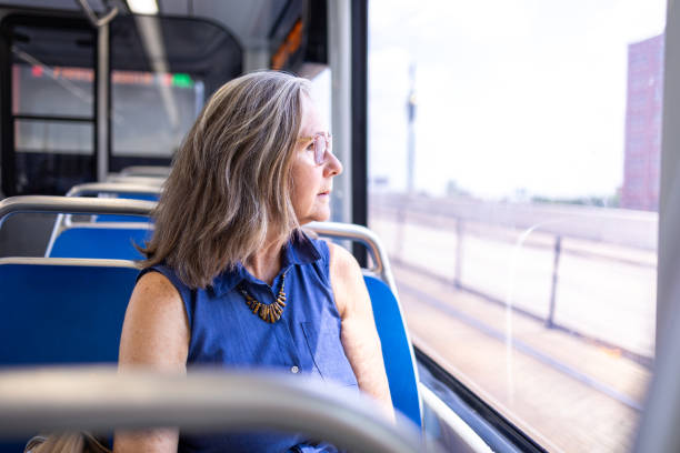 istock Senior woman looking out bus window, reflecting during a public transit ride. 2158411476