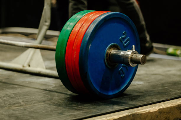 close-up barbell with red, green and blue plates on rubber floor