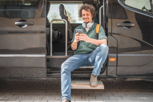 istock A bus driver with wireless headphones around his neck on a break from driving a minibus using a smartphone 2158412060