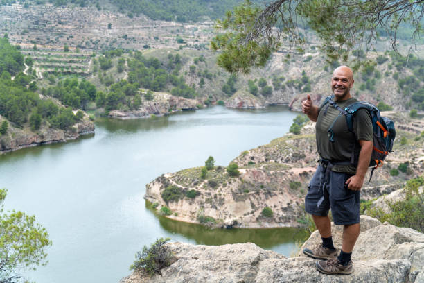 istock A strong man hiker poses smiling on a rock outdoors 2158415420