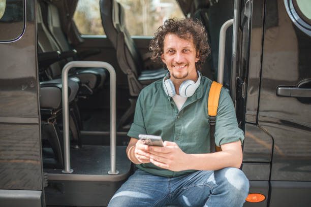 istock Portrait of a smiling van driver sitting on an open van, taking a break from driving and looking directly at the camera 2158415737