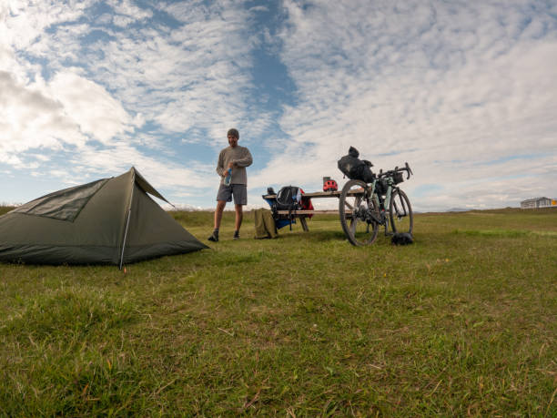 istock Cyclist Opening Water Bottle at Campsite 2158417181